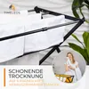 A close-up of a black drying rack with white towels, with a woman in a circular inset using a towel. Voir les images du produit