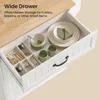 An open drawer of a white kitchen cart with a wooden top, showing organized kitchenware and decorative items. Podgląd zdjęcia produktu
