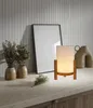 A table lamp is displayed on a countertop next to decorative vases and a framed picture. Produktbild-Vorschau