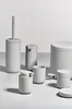 A collection of minimalist grey bathroom accessories arranged on a light grey surface against a white background. Produktbild-Vorschau