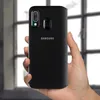 A hand holding a black Samsung flip phone case. Voir les images du produit