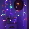 Close-up of colorful LED string lights hanging vertically, with a blurred dark circular object in the background. Produktbild-Vorschau