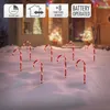 Candy canes with lights in the snow in front of a house decorated for Christmas. Voir les images du produit