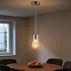 A pendant light hangs over a dining table with a bowl of fruit. Produktbild-Vorschau