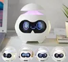 A white robot-shaped digital alarm clock with a LED display showing different faces and messages, placed on a desk next to a laptop and a plant. Produktbild-Vorschau