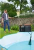 A woman is using a hose to fill a paddling pool in a garden. Náhľad obrázku produktu