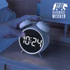 A hand is shown pressing the top of a white digital alarm clock on a wooden nightstand. Anteprima dell’immagine prodotto