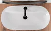 A top-down view of a white oval sink with a black faucet, placed on a wooden surface. Náhled obrázku produktu