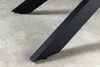 Close-up of the black metal legs of a table on a concrete floor. Produktbild-Vorschau