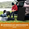 A man and his dog are packing up camping gear next to a car. Produktbild-Vorschau