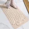 A person's feet are stepping onto a beige bath mat in a bathroom. Voir les images du produit