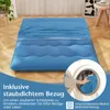 A blue mattress is laid out on a wooden floor, with text overlays and a circular inset showing a hand putting a blue fabric into a washing machine. Náhled obrázku produktu