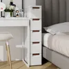 A narrow white storage cabinet with brown drawer pulls is placed next to a bed and a white desk. Produktbild-Vorschau