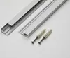 Two aluminum profiles and two screws with wall plugs are laid out on a white surface. Produktbild-Vorschau
