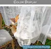A close-up of a white lace curtain with floral embroidery, draped over a table set for a picnic outdoors. Náhľad obrázku produktu