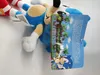 A Sonic the Hedgehog plush toy is lying on a white surface, with a folded tag displaying game graphics and text. Produktbild-Vorschau