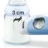 Close-up of a baby bottle with milk and a digital thermometer measuring the temperature. A measurement indicator shows '3 cm'. Produktbild-Vorschau