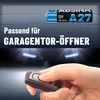 A hand holding a car key fob in front of a blurred background of headlights and a garage door. Produktbild-Vorschau