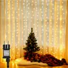 A decorated Christmas tree with gifts and a blanket in front of a window with string lights. Náhľad obrázku produktu