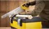 A person is using a saw to cut a piece of wood, with a toolbox in the foreground. Anteprima dell’immagine prodotto