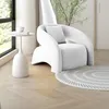 A white armchair is placed next to a window with a small side table and a rug on a wooden floor. Anteprima dell’immagine prodotto