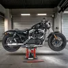 A black motorcycle is lifted on a red hydraulic lift in a garage. Produktbild-Vorschau