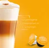 A close-up of a layered coffee drink with two coffee capsules in the foreground, set against an orange background with text. Voir les images du produit
