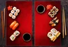 A top-down view of sushi and soy sauce on red placemats. Náhľad obrázku produktu