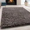 A shaggy rug in a living room setting with a fireplace and a blue ottoman. Náhled obrázku produktu