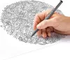 A hand is shown holding a pen and drawing on a detailed coloring page. Produktbild-Vorschau