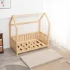 A wooden toddler bed frame with a mattress laid out on the floor next to it, in a room with white paneled walls and a patterned rug. Anteprima dell’immagine prodotto