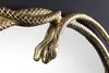 A close-up of a gold-colored snake sculpture forming the frame of a mirror. Produktbild-Vorschau