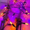 A close-up of Halloween-themed decorative skeleton parts (knees and hands) wrapped in purple and orange LED string lights. Produktbild-Vorschau