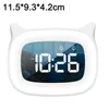 A white digital alarm clock with cat ears is displayed on a white background. The clock face shows the time 10:26 AM and two bell icons, indicating alarm settings. A person is visible sleeping in the background reflection on the clock face. Produktbild-Vorschau