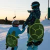 Two people in ski gear with turtle-shaped backpacks on a snowy slope. Podgląd zdjęcia produktu