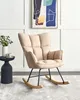 A beige upholstered rocking chair with black metal legs and wooden rockers, placed on a light gray rug in a room with white paneled walls and a framed abstract painting. Náhled obrázku produktu