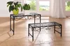 Two black metal plant stands with decorative scrollwork are placed on a wooden floor in front of a window with white curtains. Produktbild-Vorschau