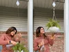 A woman is watering a hanging plant on a porch. Náhled obrázku produktu
