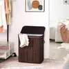 A laundry basket in a bedroom setting, next to a clothing rack and a bed. Produktbild-Vorschau