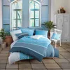 A bedroom scene with a bed dressed in blue striped bedding, set against a backdrop of blue shutters and windows. Produktbild-Vorschau