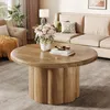 A living room scene with a round coffee table in the foreground, a sofa and armchair in the background, and decorative items. Produktbild-Vorschau