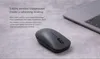 A dark gray wireless mouse is placed on a textured gray surface next to a laptop. Anteprima dell’immagine prodotto