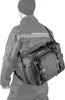 A person wearing a jacket and beanie is carrying a black motorcycle bag over their shoulder. Produktbild-Vorschau