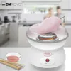 A cotton candy maker is shown on a countertop with a bowl of pink sugar and sticks, with a blurred background of a kitchen and two people. Podgląd zdjęcia produktu