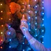 A hand is interacting with a string of lights that are illuminating a moss wall. Náhled obrázku produktu
