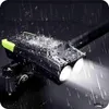 A black and green bicycle light with two bright white lights is shown mounted on a bicycle handlebar, with water droplets on the light and a dark, wet surface below, suggesting it is waterproof and being used in the rain. Podgląd zdjęcia produktu