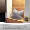 A grey pillow on a wooden bench with a wooden wall behind it. There is a logo in the bottom right corner. Produktbild-Vorschau