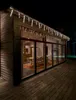 A modern house with large windows at night, decorated with icicle lights. Produktbild-Vorschau