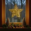 A decorative star light hanging in a window at dusk, with Christmas decorations on the windowsill. Anteprima dell’immagine prodotto