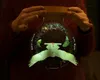 A person holds a glass orb containing a 3D owl and glowing particles, with text around the orb. Produktbild-Vorschau